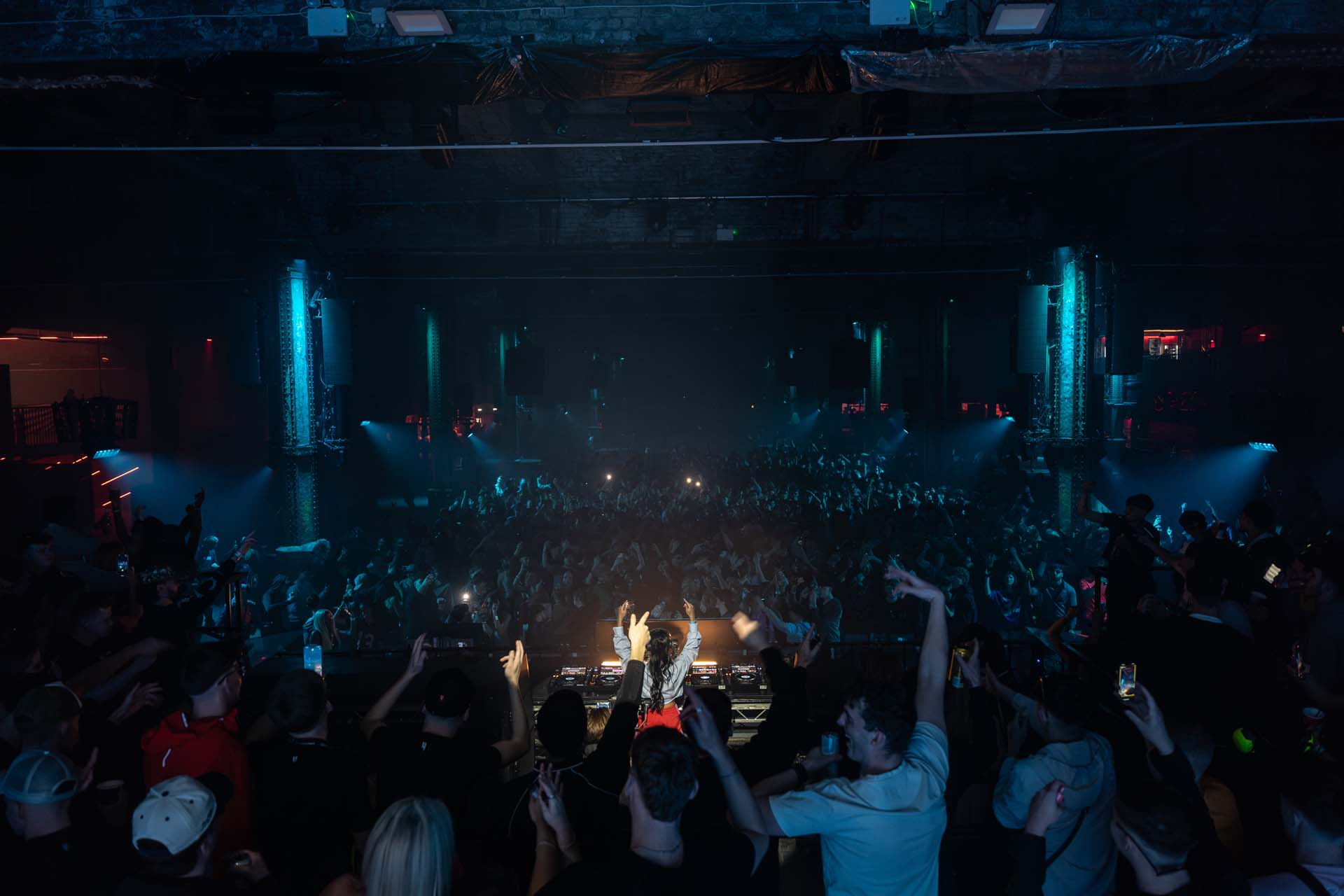 Concert scene with a crowd in a dark venue, illuminated by stage lights.
