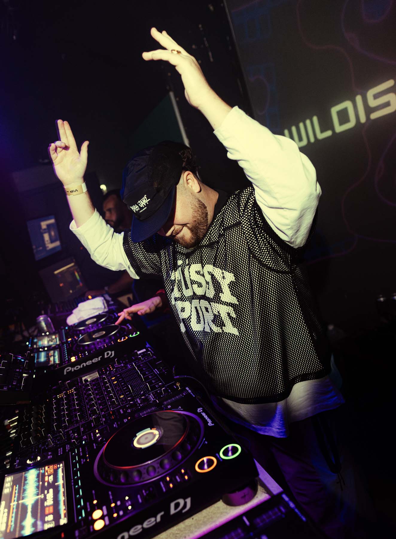 DJ performing at a club with equipment and 'Wildside' branding in the background