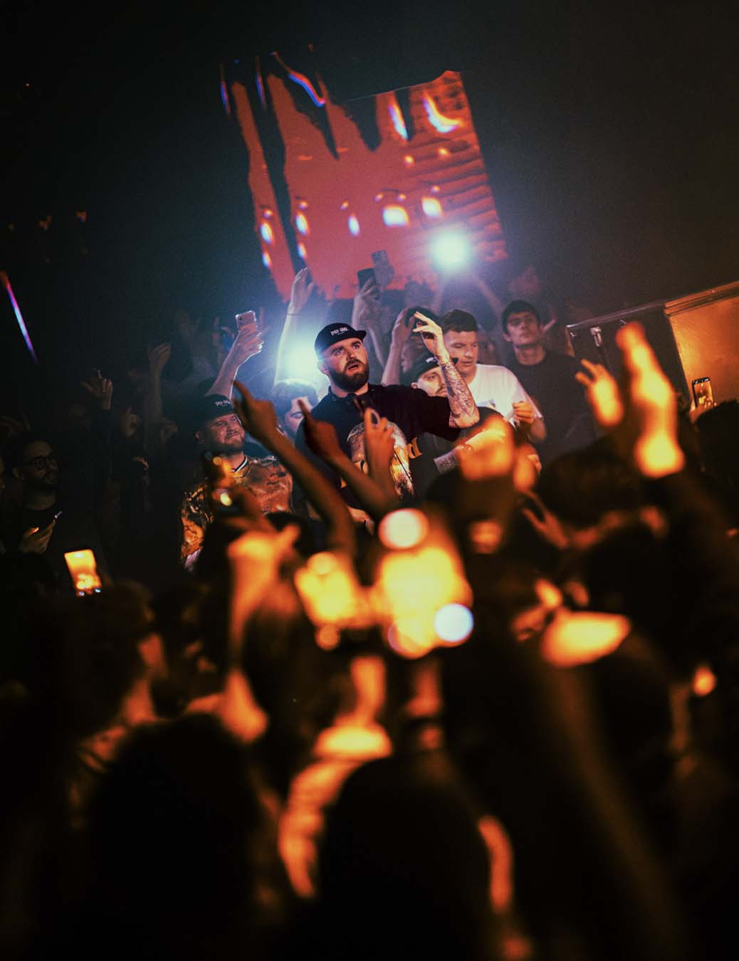 Concert scene with a performer on stage and audience members holding up phones.