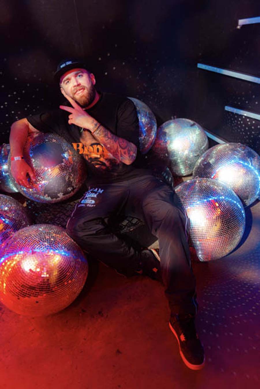 Gaskin posing with disco balls in a dark room with colorful lighting