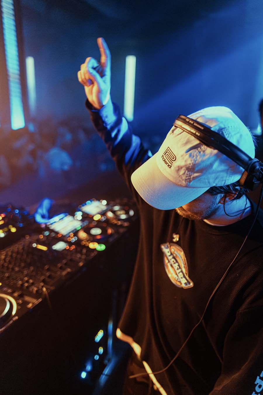 DJ at a music event with equipment and crowd in the background