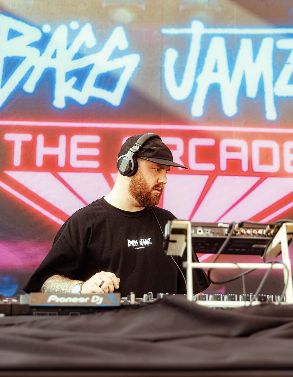 Caul.e dj at a turntable with 'Bass Jamz' branding in the background