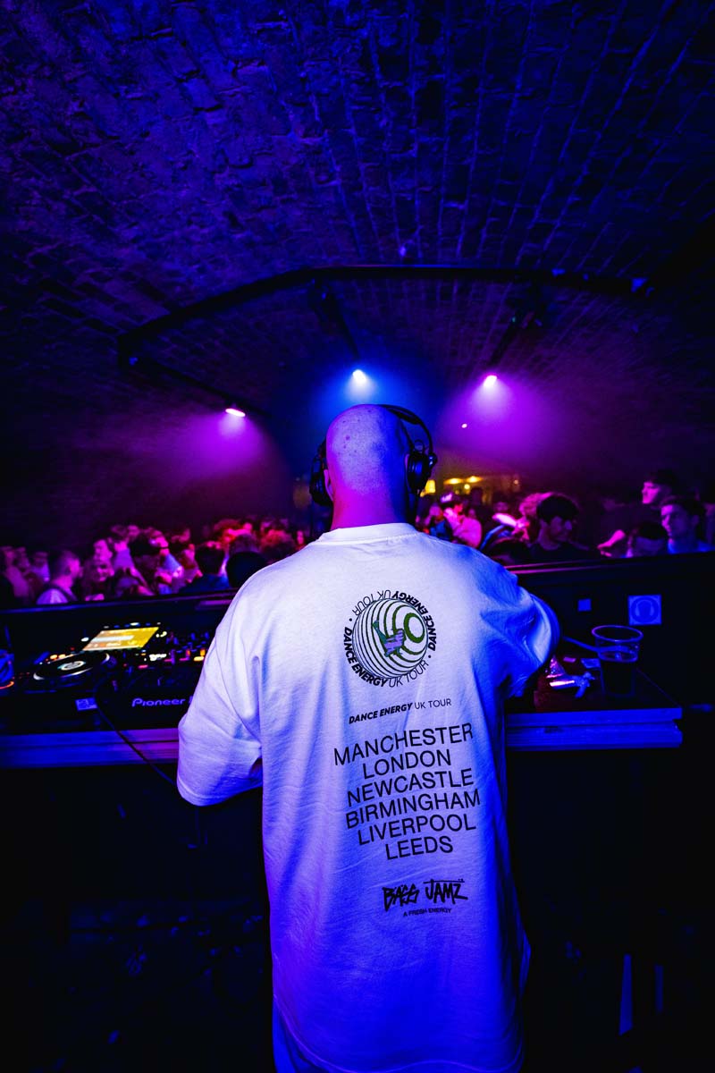 DJ at a nightclub with a white t-shirt displaying text.