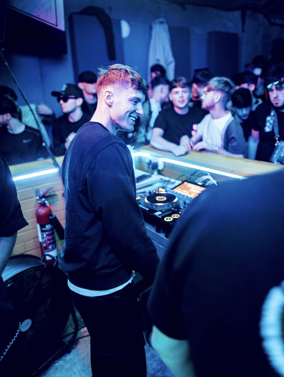 DJ at a music event with a crowd in a dimly lit venue