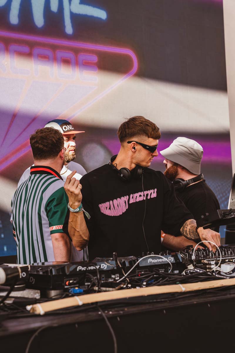 DJ performing at a music event with colorful lights in the background