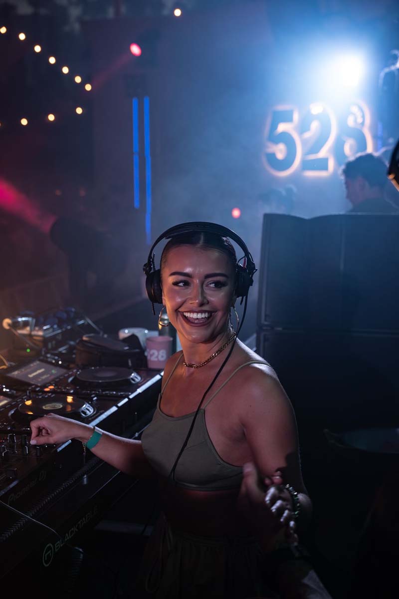 DJ at a music event with '528' visible in the background