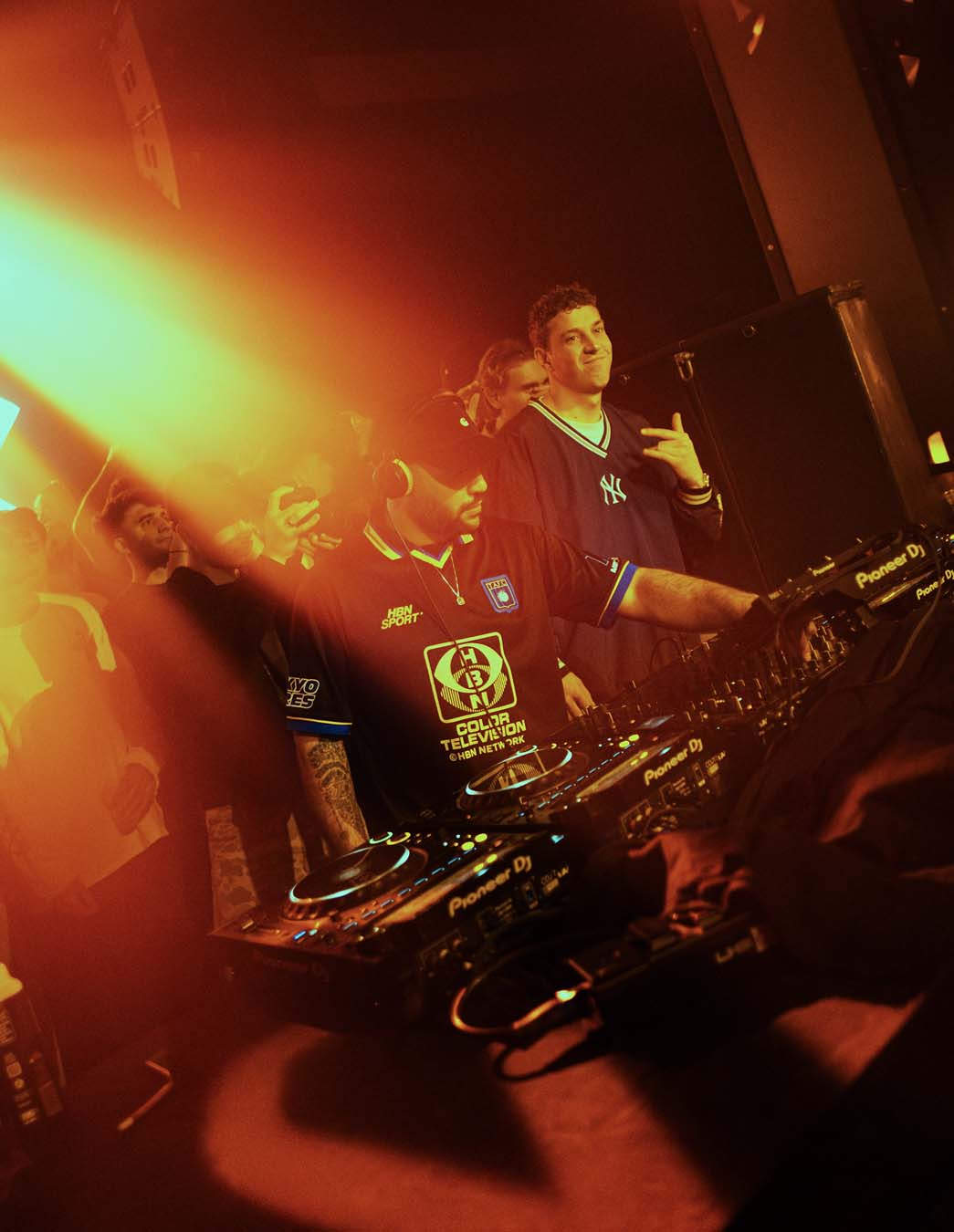 DJ performing at a club with equipment and red lighting