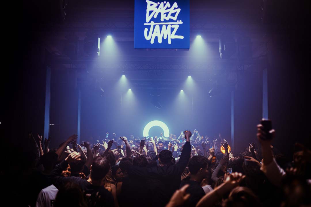 Concert scene with a crowd and stage lights, featuring the 'Bass Jamz' logo.